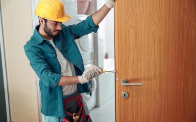 Locksmith workman in uniform installing door knob. Professional repair service. Maintenance Concept