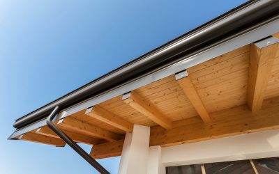 New wooden warm ecological house roof with steel gutter rain system. Professional construction and drainage pipes installation. Eco materials.